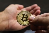 Ilustrasi tangan memegang smartphone menampilkan grafik Bitcoin, melambangkan kemudahan akses dan potensi investasi aset digital. Latar belakang menunjukkan koin Bitcoin yang berkilauan, menggambarkan nilai dan daya tariknya di pasar finansial modern.