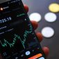 Grafik harga aset kripto yang berfluktuasi tajam, menggambarkan volatilitas tinggi pasar digital yang bisa membawa keuntungan besar sekaligus kerugian mendalam. Seorang investor terlihat cemas memantau layar laptopnya, merefleksikan tekanan psikologis yang kerap dialami dalam dunia investasi kripto yang tidak terduga.