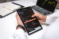 Seorang trader sedang menganalisis grafik pergerakan harga aset kripto pada layar komputer, menunjukkan fokus dan ketelitian yang diperlukan dalam membuat keputusan investasi. Berbagai indikator teknikal terlihat jelas, membantu dalam memprediksi arah pasar.
