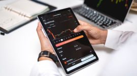 Seorang trader sedang menganalisis grafik pergerakan harga aset kripto pada layar komputer, menunjukkan fokus dan ketelitian yang diperlukan dalam membuat keputusan investasi. Berbagai indikator teknikal terlihat jelas, membantu dalam memprediksi arah pasar.