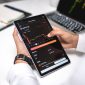 Seorang trader sedang menganalisis grafik pergerakan harga aset kripto pada layar komputer, menunjukkan fokus dan ketelitian yang diperlukan dalam membuat keputusan investasi. Berbagai indikator teknikal terlihat jelas, membantu dalam memprediksi arah pasar.