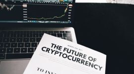 Ilustrasi seorang individu sedang mempelajari grafik harga Bitcoin di layar laptop, dengan dompet digital dan koin Bitcoin fisik sebagai simbol investasi aset digital. Gambar ini merepresentasikan proses riset dan analisis yang perlu dilakukan investor pemula sebelum terjun ke dunia kripto.
