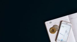 Ilustrasi tangan memegang koin Bitcoin virtual di depan grafik pertumbuhan pasar kripto yang menunjukkan potensi dan dinamika investasi aset digital. Gambar ini merepresentasikan peluang serta tantangan yang dihadapi para investor pemula di dunia Bitcoin.
